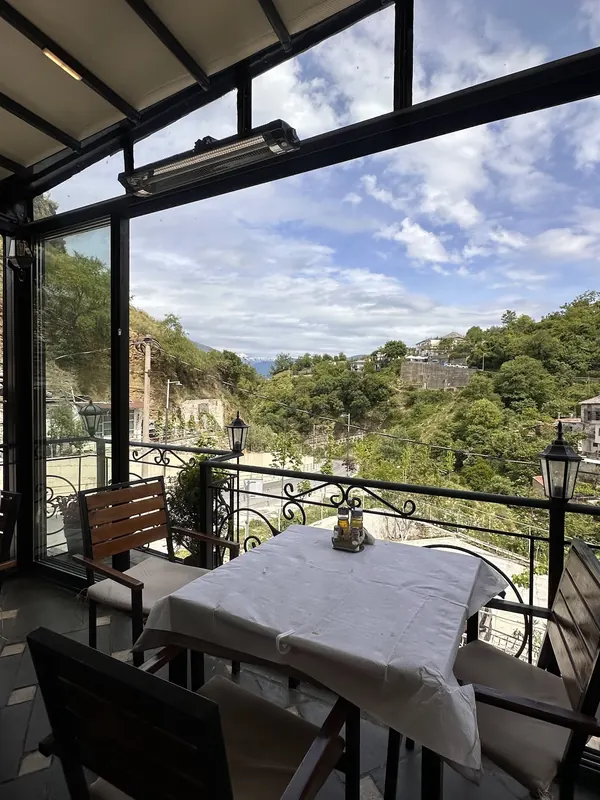 The glass-walled dining room open to the hills of Gjirokastër on a sunny day