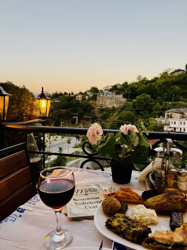 A glass of red wine and a traditional mixed plate on the terrace at sunset