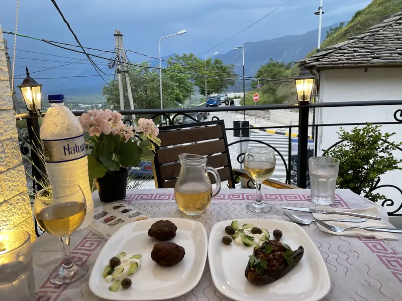 Dinner on the terrace at dusk: qofte, stuffed eggplant and a glass of wine, mountains behind